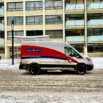 blue and white van parked near white concrete building during daytime