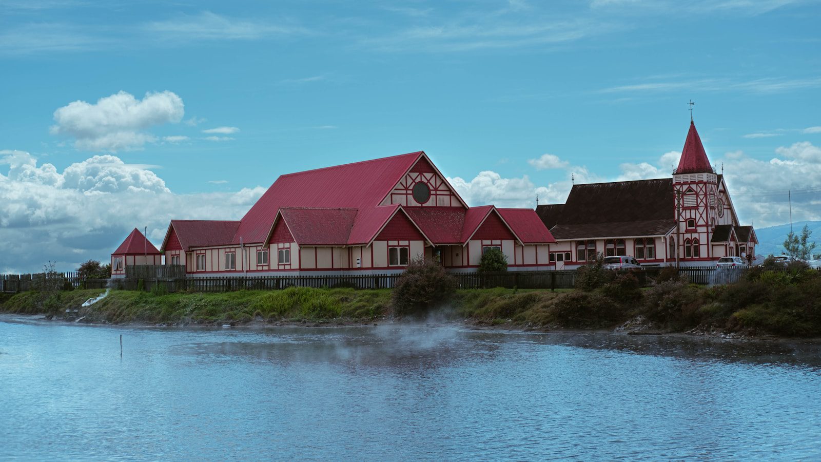 a large building with a red roof next to a body of water