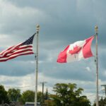 Canadian and American flags waving under a cloudy sky in Harbor Beach, MI.
