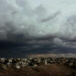 Ominous storm clouds over a city landscape illustrating the gathering storm of the Iran war.