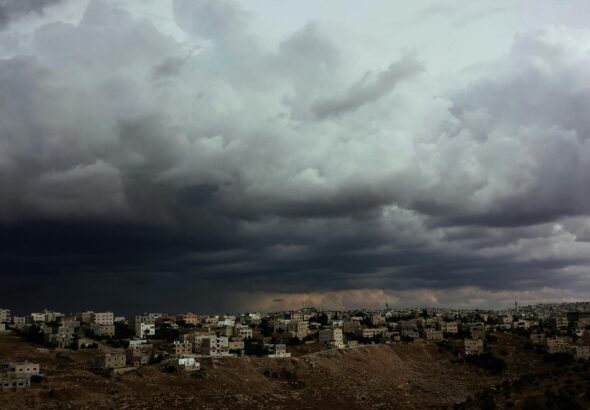 Ominous storm clouds over a city landscape illustrating the gathering storm of the Iran war.