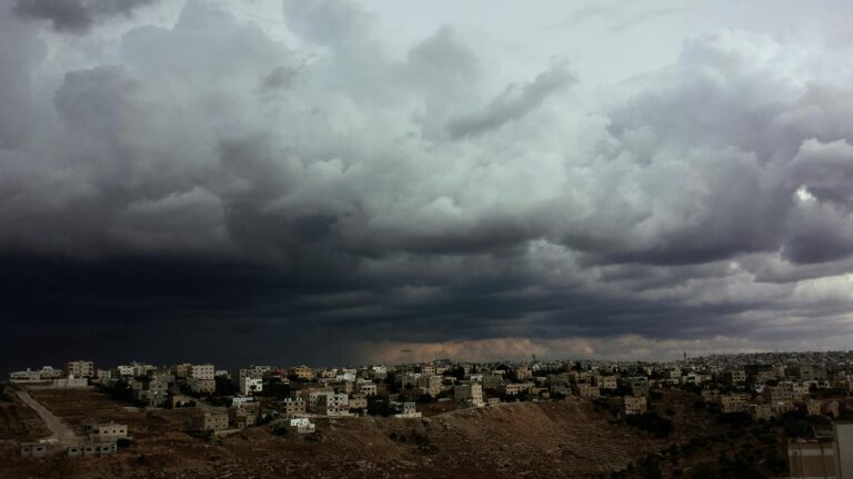 Ominous storm clouds over a city landscape illustrating the gathering storm of the Iran war.