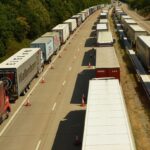 Trade War Fatigue: Long lines of transport trucks at a Canada-U.S. border crossing symbolize ongoing tariff disputes between Canada and the United States.