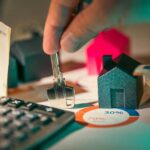 hand holding key over house models