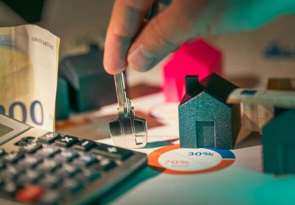 hand holding key over house models