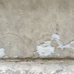 A detailed view of a cracked concrete wall showcasing weathered textures and patterns.