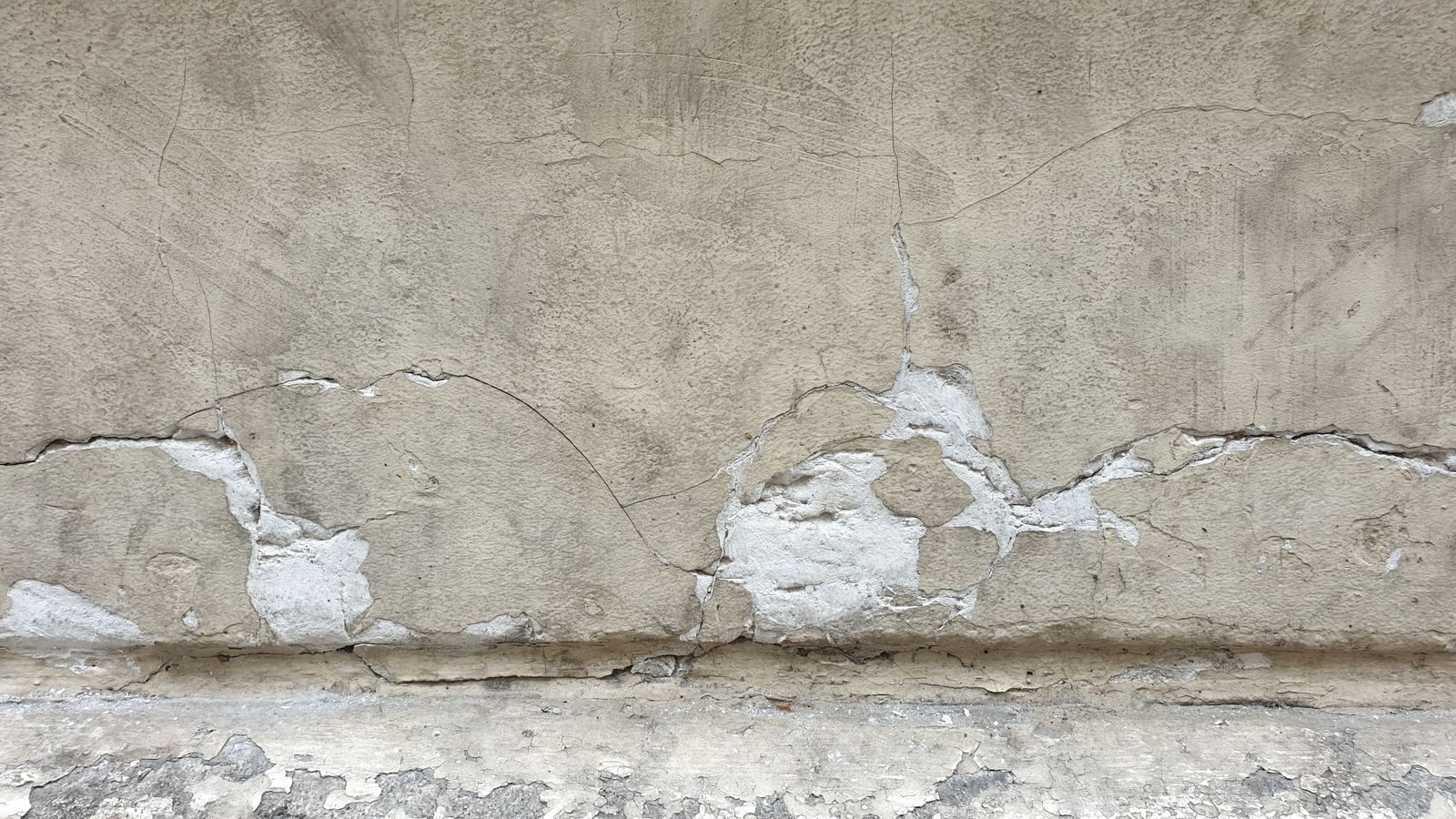 A detailed view of a cracked concrete wall showcasing weathered textures and patterns.